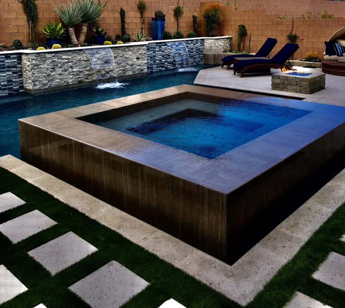 A pool with a large square shaped hot tub.
